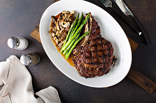 An image of a grilled steak with asparagus and mushrooms.