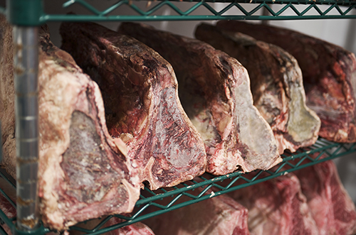 An image of beef on racks during the dry aging process.