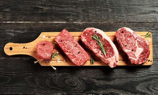 Different cuts of steaks on a cutting board.