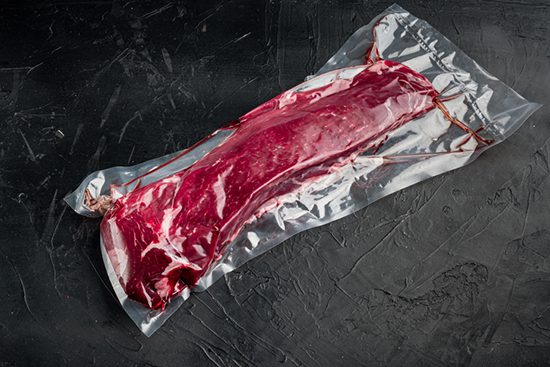 A vacuum-packed cut of raw beef that is wet aging. 